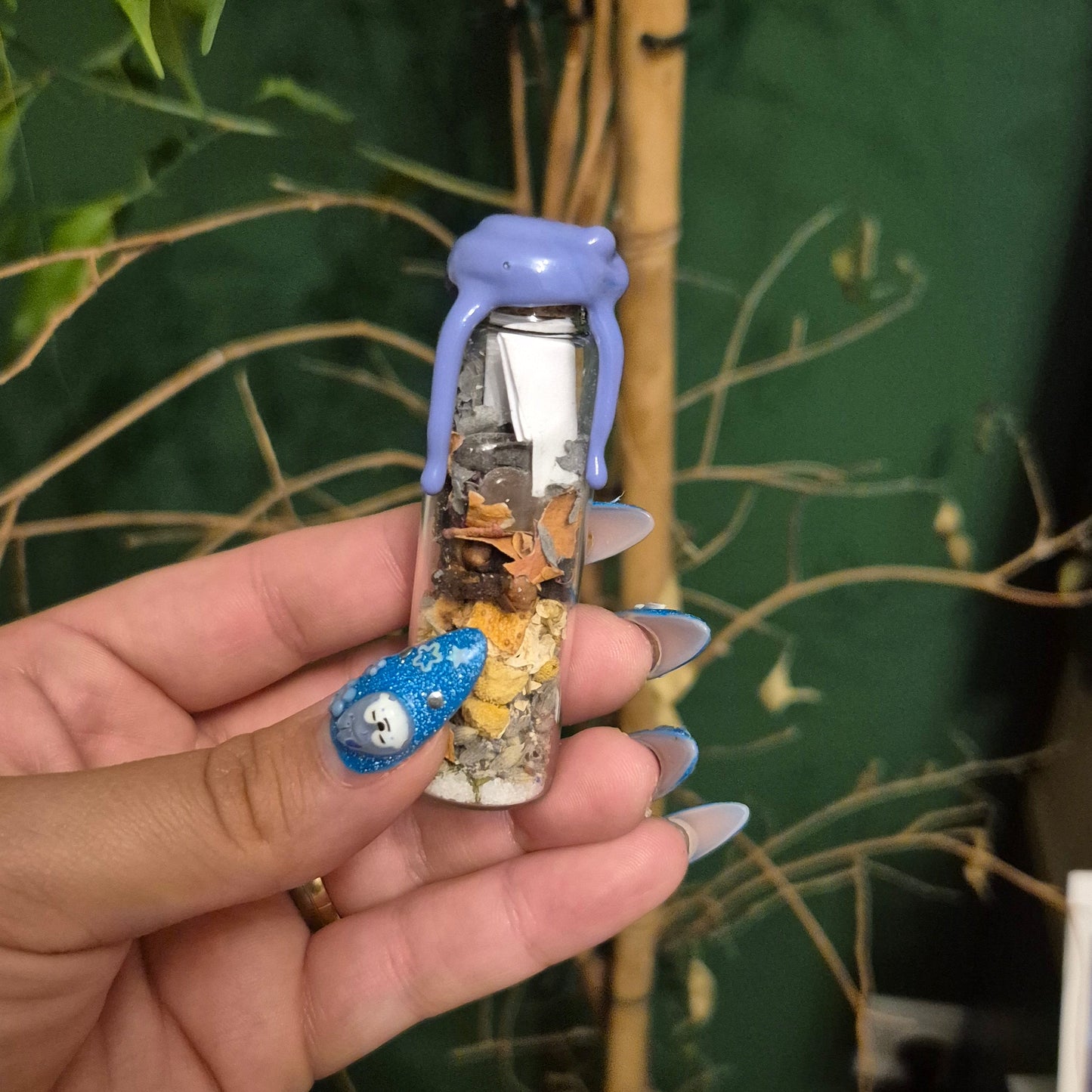 Hand holding a little spell in a bottle herb and crystal bled to soothe anxiety