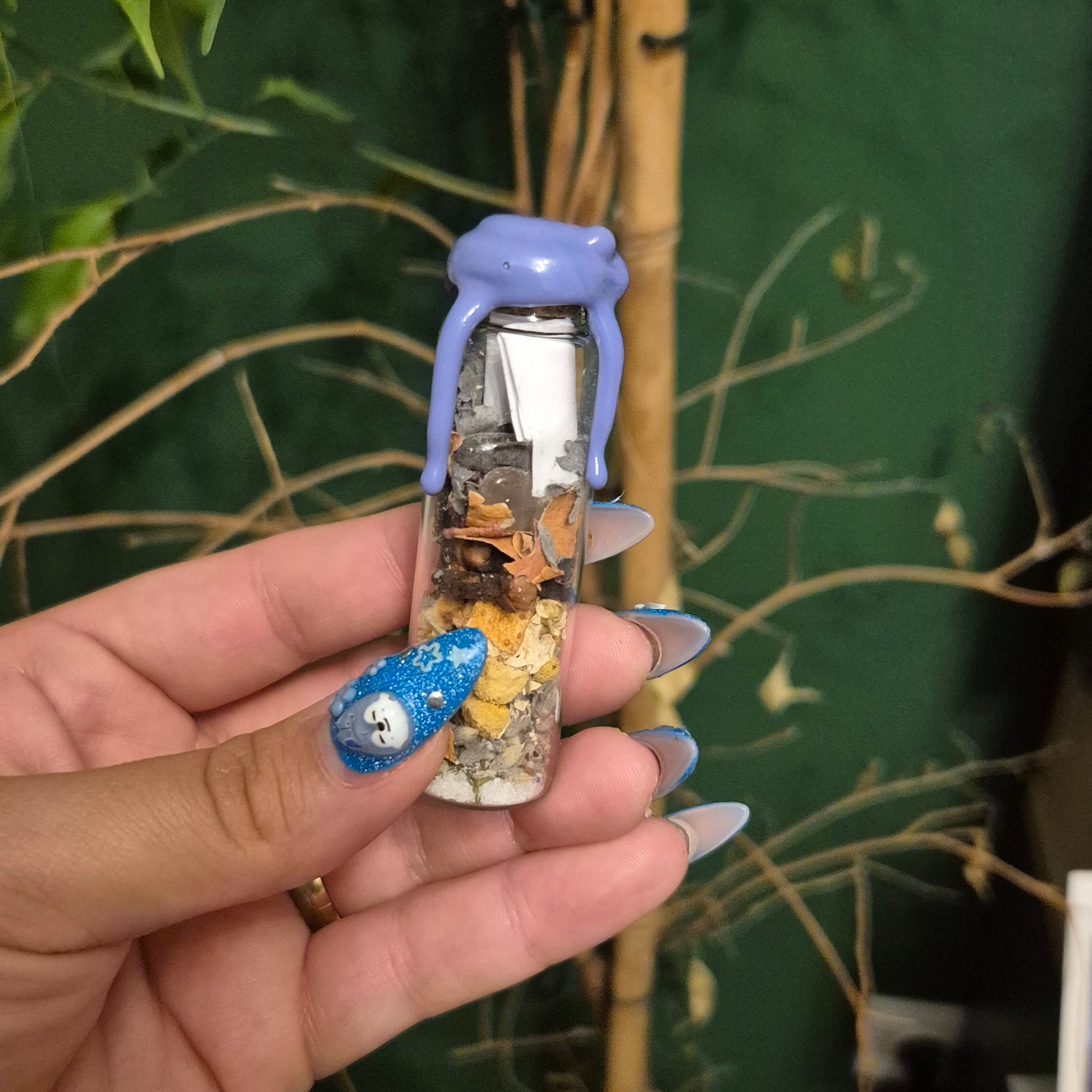 Hand holding a little spell in a bottle herb and crystal bled to soothe anxiety